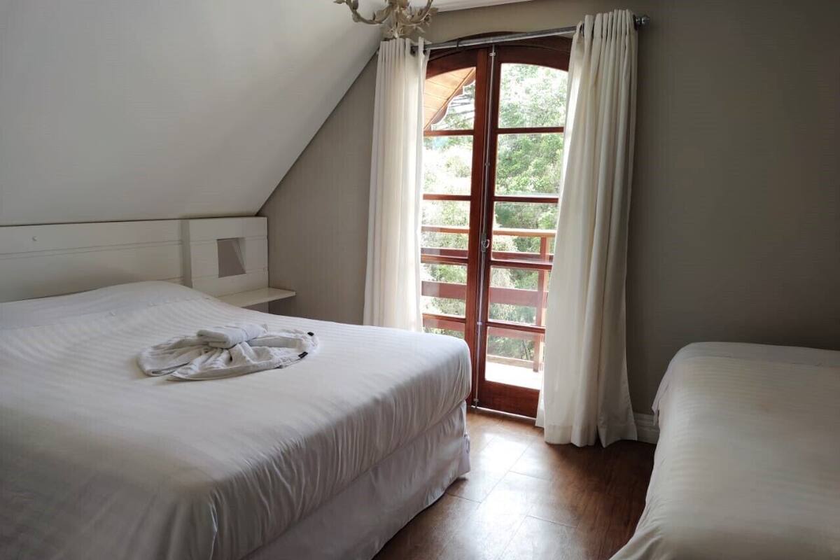 Une chambre avec un grand lit, une table de chevet et une fenêtre avec des rideaux.