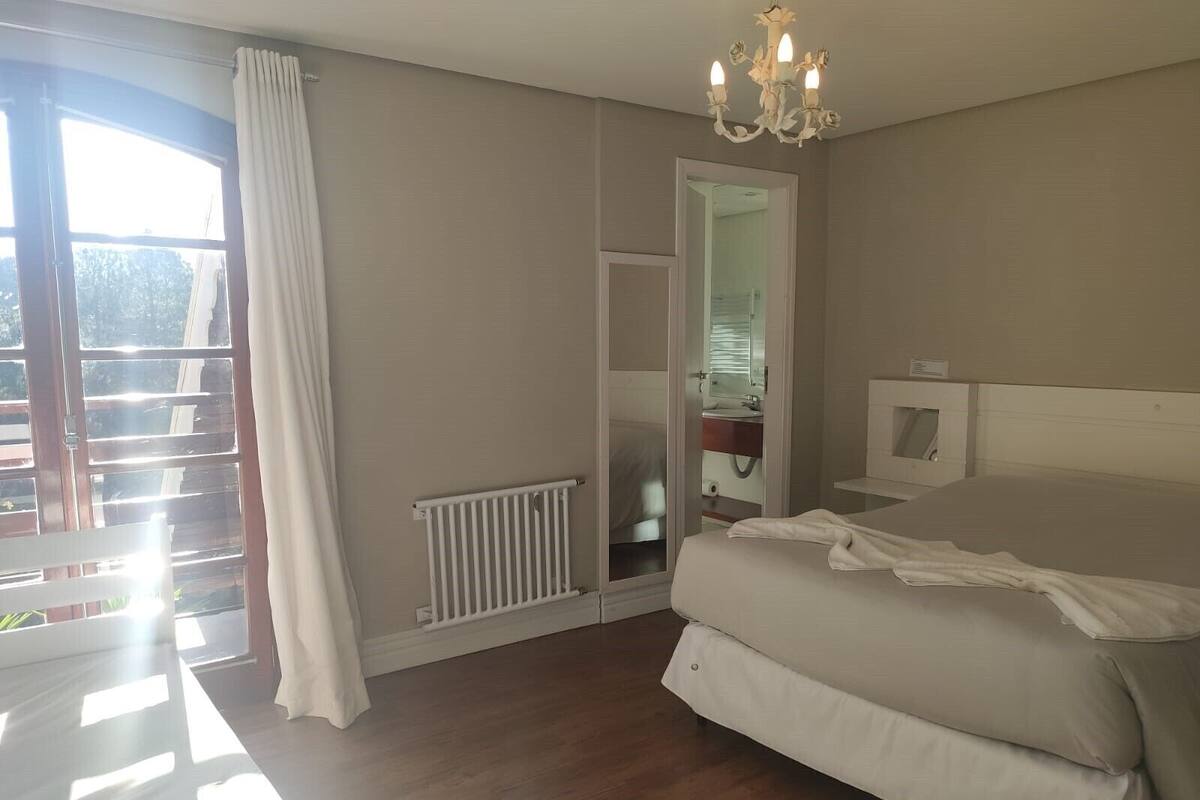 Une chambre à coucher avec un lit, un radiateur, une fenêtre avec des rideaux et un lustre.