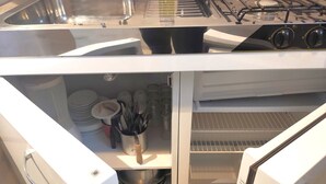 Een keuken met een roestvrijstalen spoelbak, een gasfornuis en een inbouwoven.