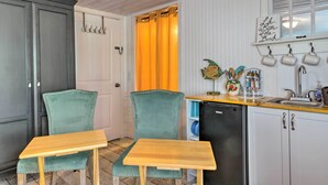 Een kleine keuken met een eethoek, met een koelkast, een wastafel en een tafeltje met stoelen.