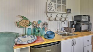 Een keuken met een houten aanrecht, een spoelbak, een broodrooster en een afdruiprek. Op het aanrecht staan borden, kommen en een koffiezetapparaat.