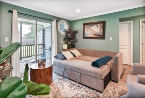 A living room with a sofa, armchairs, a coffee table, and a large window with a view of a deck.