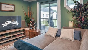 Un salon avec un canapé, un téléviseur et une fenêtre donnant sur une terrasse.