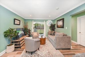 A living room with a television, two sofas, a coffee table, and a large window.