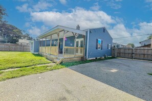 Einbungalow mit überdachter Veranda und einem umzäunten Garten.