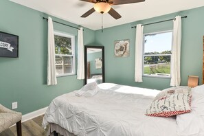 Une chambre à coucher avec un lit, un ventilateur de plafond, une fenêtre et une vue sur l’extérieur.