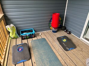 Une terrasse en bois équipée de matériel d’exercice, une caisse bleue et un sac de paillis.
