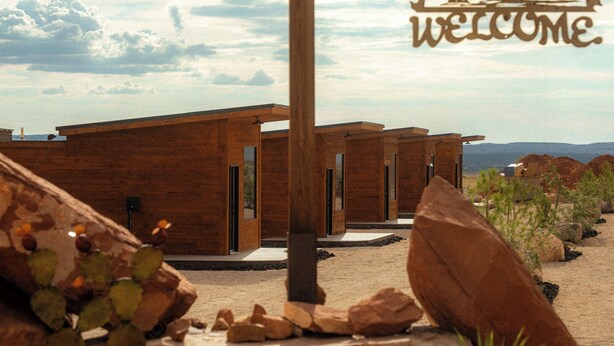Un edificio de estilo desértico con un letrero que dice 'WELCOME', con un diseño arquitectónico moderno que incluye ventanas amplias y techo plano.