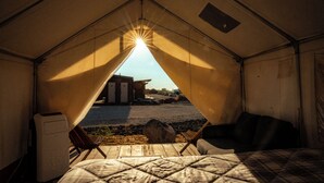 Una carpa con una cama, una silla y una mesita.