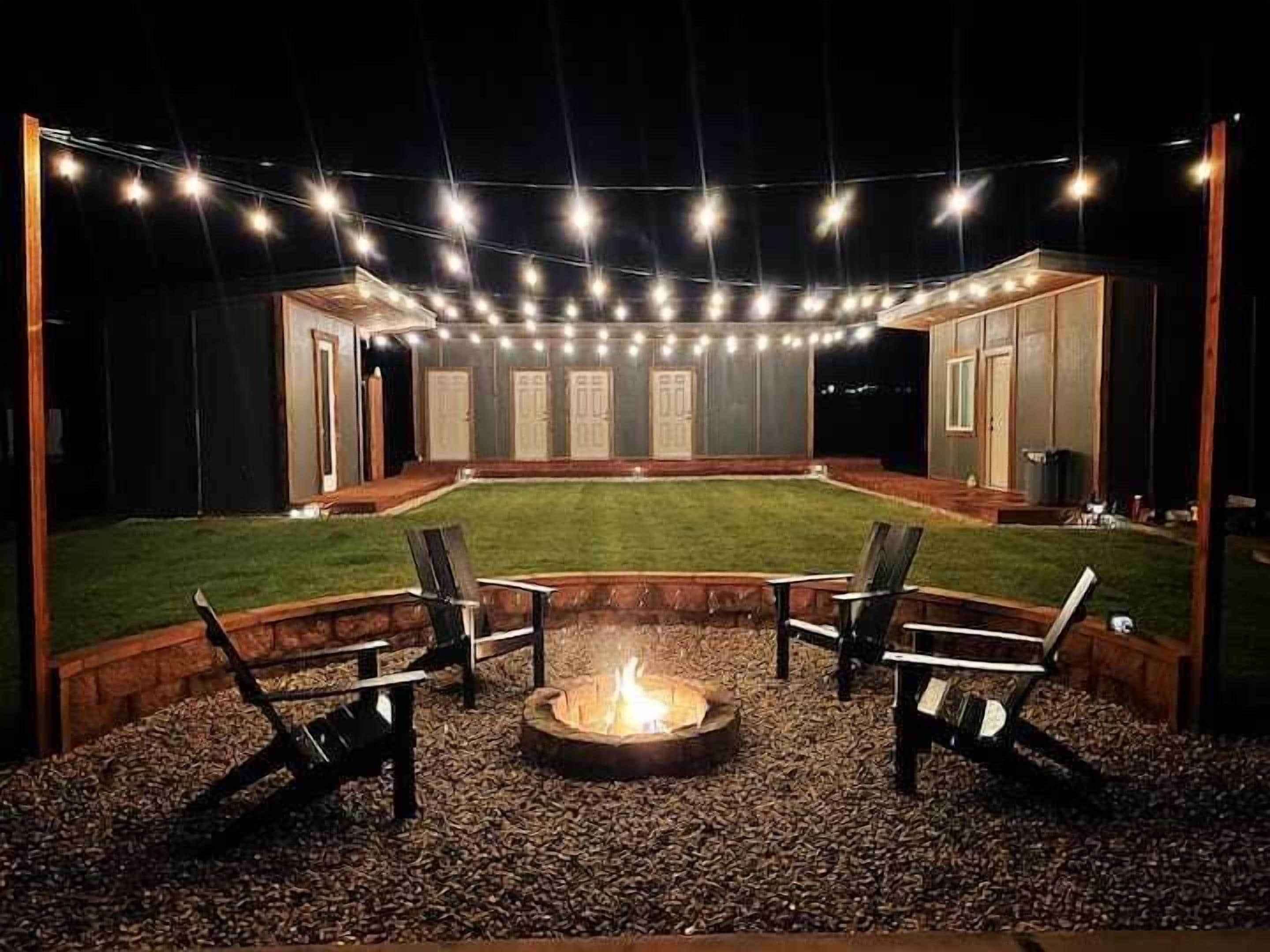 Ein Garten mit Feuerstelle, Sitzgelegenheiten und Lichterketten.