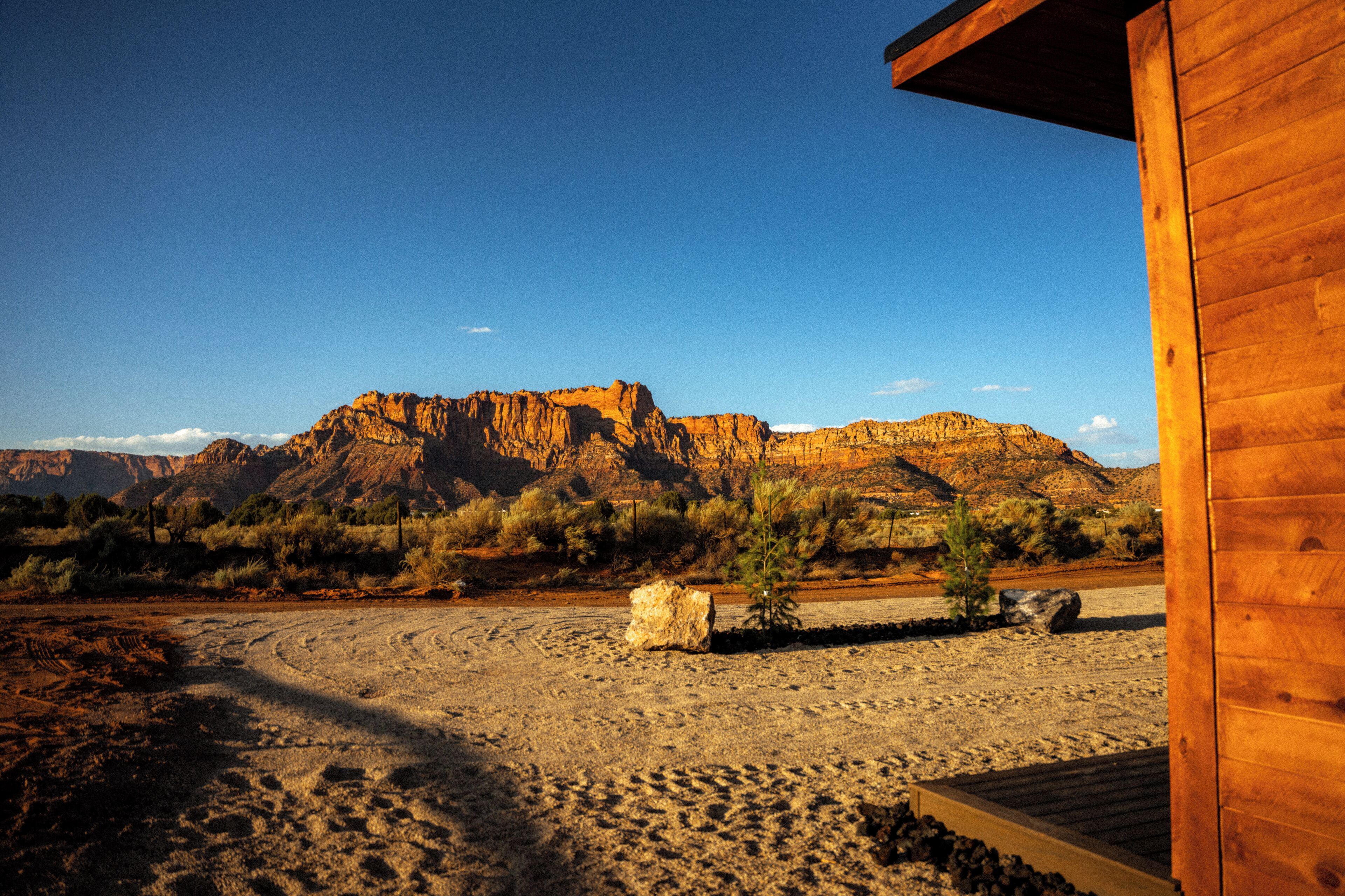 A desert landscape with a wooden building, a clear sky, and a mountain in the background.