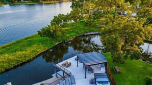 A lakeside property with a dock, outdoor seating area, and a covered patio. - Lakefront Home. Insane Views - Pool/Spa! Gameroom! (Kingsland)