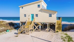 A two-story beach house with a blue door, wooden stairs, and a wooden deck. - "Island Time", Peaceful 5BR Oceanfront Cottage (Surf City)