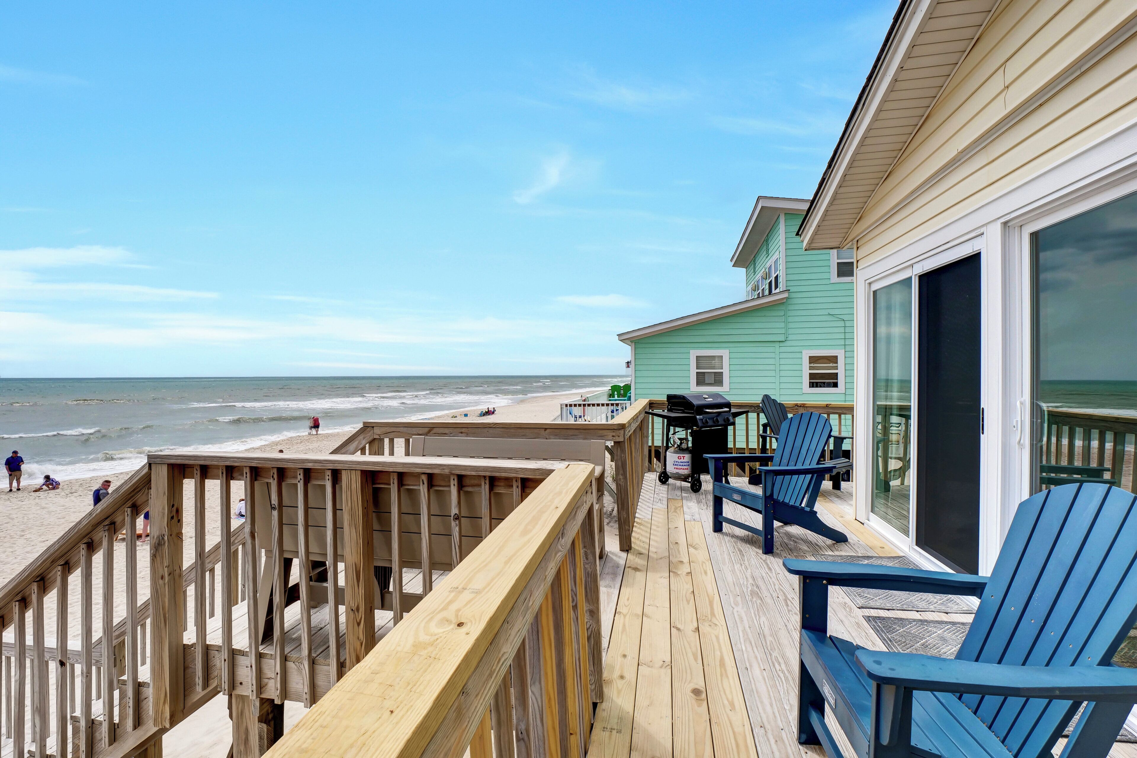 Eine Holzterrasse mit Blick auf den Strand und den Ozean.