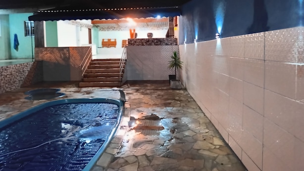 An indoor pool area with a stone floor, a small pool, and a staircase leading to a covered area.