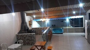 An outdoor patio with a barbecue area, a pool, and a dining setup.