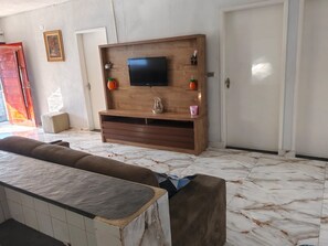 Ein Wohnzimmer mit einer Holzeinbauwand, einem Flachbildfernseher und einem Marmorboden.