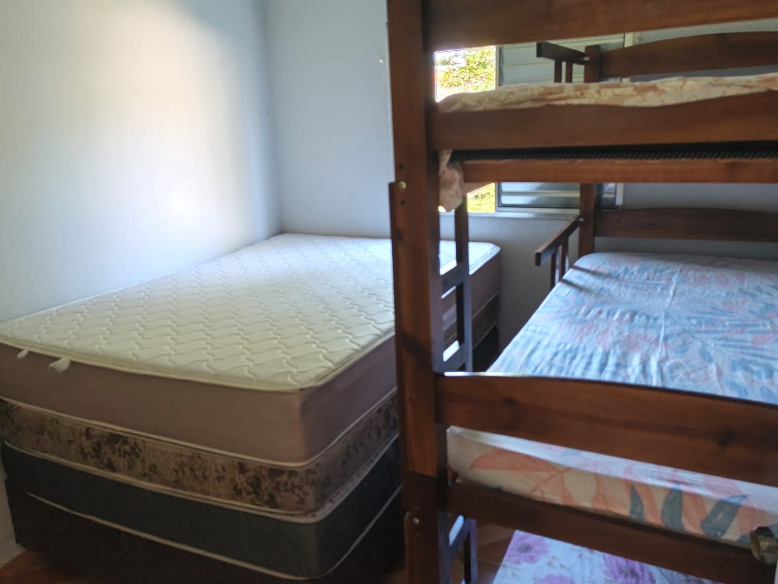 A bunk bed with a mattress and a lower bunk with a patterned blanket.