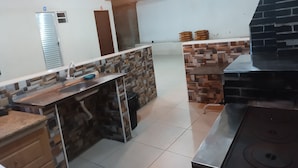 A kitchen with a stone backsplash, a stainless steel countertop, and a brick oven.