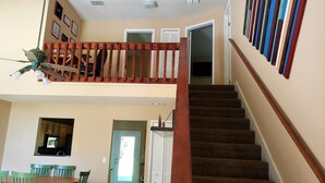 Una escalera que lleva a un segundo piso, con un comedor debajo.