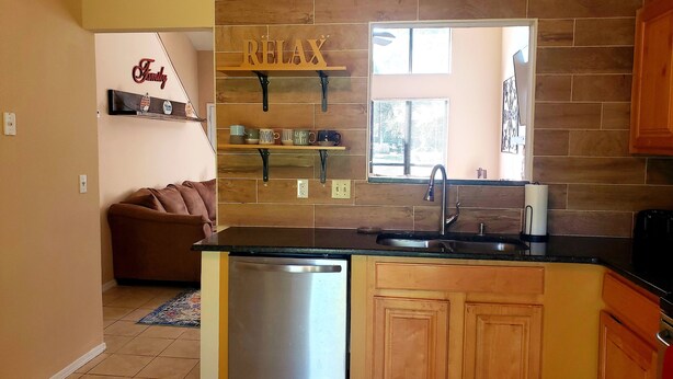 Una cocina con armarios de madera, lavavajillas y un cartel que dice 'Relax'.