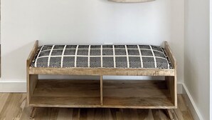 A wooden bench with a patterned cushion, a wall-mounted luggage rack, and a hanging bag with the word "GETAWAY" on a white wall. - Sparkling East Hampton Oasis 3 bed 2 bath w/heated pool. Pets Welcome! (East Hampton)