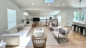 A spacious living room with a large sofa, a coffee table, and a dining area with a high table and chairs. - Sparkling East Hampton Oasis 3 bed 2 bath w/heated pool. Pets Welcome! (East Hampton)