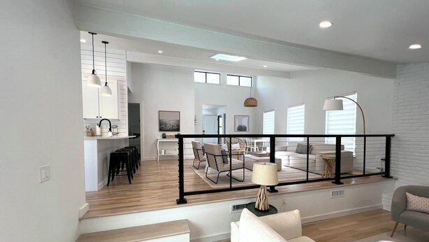 A spacious living area with a staircase leading to a kitchen, a dining area, and a balcony with a railing. - Sparkling East Hampton Oasis 3 bed 2 bath w/heated pool. Pets Welcome! (East Hampton)