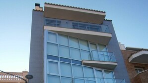 A multi-story building with large windows, a visible balcony on the upper floor, and a garage entrance at the bottom.