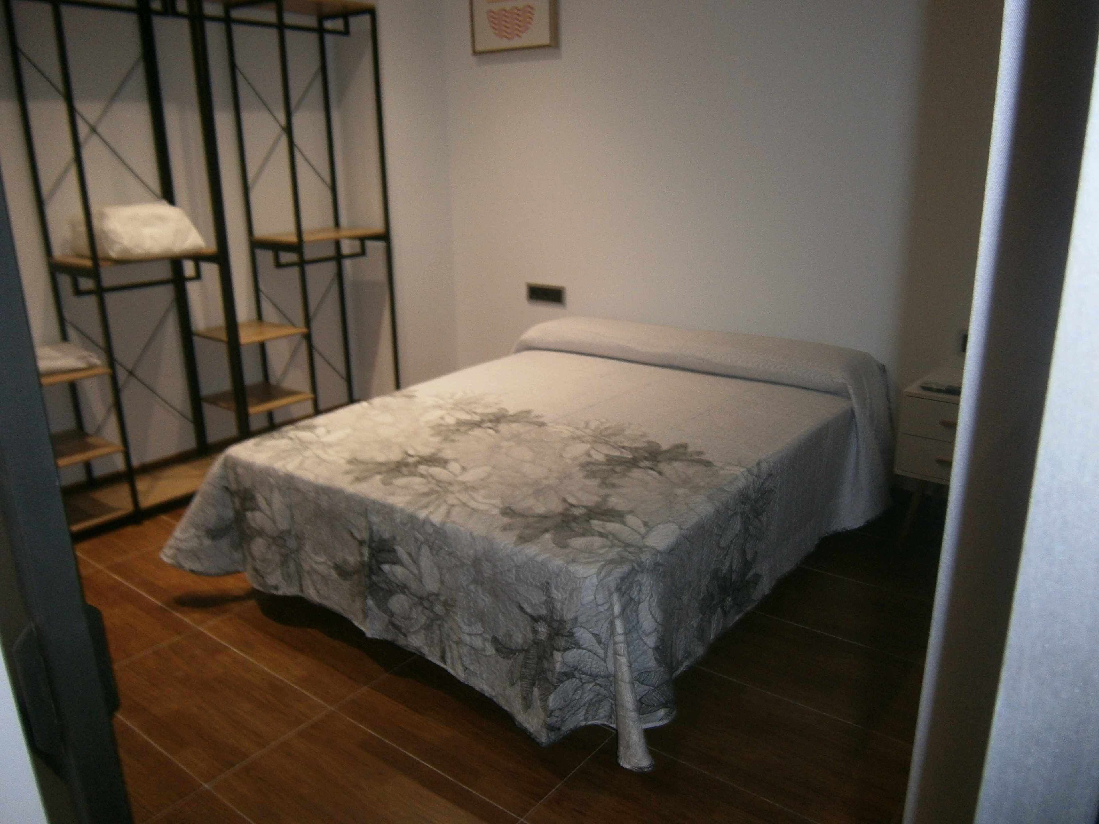 Un dormitorio con cama, armario y estantería.