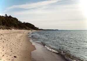 A beach with a sandy shore and a forested hill in the background.