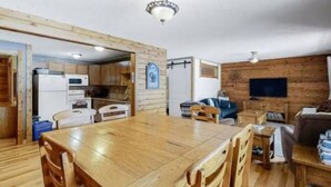A wooden interior with a dining table, chairs, a sofa, and a TV. - Lakefront Suite w/ Private Hot Tub | Fireplace (Naramata)