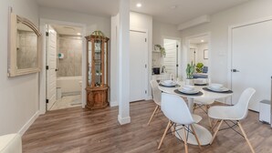 A modern kitchen with white cabinets, a wooden dining table, and a built-in oven. - Enjoy this Brand New Cozy 2BR Guest Suite in YYC! (Calgary)