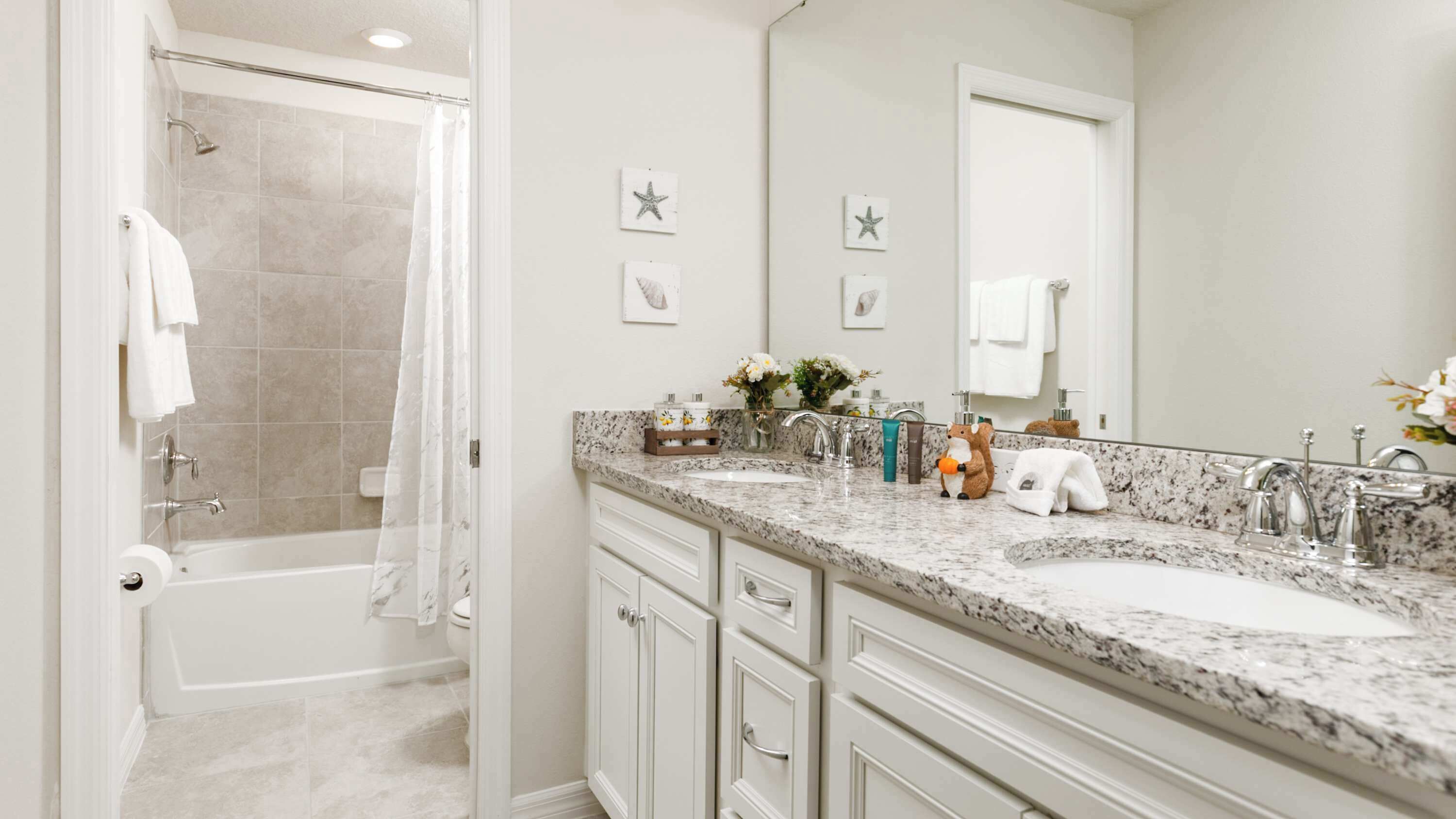 A modern bathroom with a shower, two sinks, a large mirror, and a towel rack.