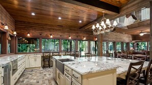 A spacious kitchen with a large island, wooden ceiling, and large windows offering a view of the outdoors. - Spacious Riverside Lodge on 370 acres near Tuscaloosa, 8 bedrooms - sleeps 15 (Gordo)