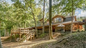 A rustic cabin with a wooden deck, stone walls, and a covered outdoor seating area. - Spacious Riverside Lodge on 370 acres near Tuscaloosa, 8 bedrooms - sleeps 15 (Gordo)