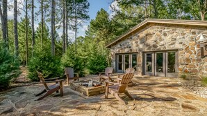 A stone building with a fire pit and Adirondack chairs in a forest setting. - Spacious Riverside Lodge on 370 acres near Tuscaloosa, 8 bedrooms - sleeps 15 (Gordo)