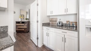 Eine moderne Küche mit weißen Schränken, Granit-Arbeitsplatten und einem eingebauten Toaster.