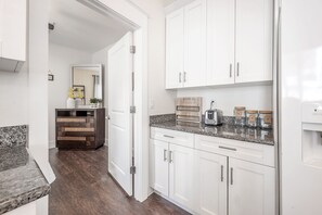 Una cocina moderna con armarios blancos, encimeras de granito y un tostador empotrado.