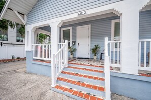Uma casa com varanda, degraus e uma porta com o número 6012.