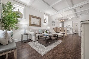 Een moderne woonkamer met een donkerhouten salontafel, een beige bank en een grote groene plant.