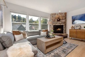 A modern living room with a stone fireplace, a sofa, a coffee table, and a TV.