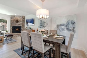 A dining area with a fireplace, a chandelier, and abstract art on the walls.