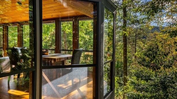 Une pièce fermée par des parois de verre, avec un plafond en bois, une table et des chaises.