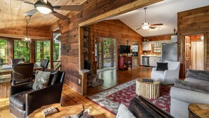 Un intérieur de cabine spacieux avec un plafond en bois, une cheminée, un coin repas et une cuisine.