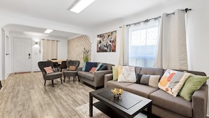 Un salon moderne comprenant un canapé, des fauteuils, une table basse et un coin repas.