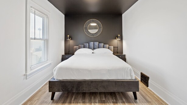Une chambre à coucher moderne avec un grand lit, un miroir rond et deux lampes de chevet.