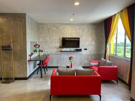 Uma sala de estar moderna com um sofá vermelho, uma mesa de jantar com cadeiras, uma TV fixada na parede e uma janela grande com cortinas.