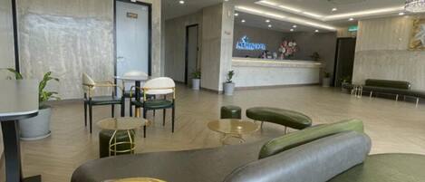A modern hotel lobby with a reception desk, seating area, and a reception counter.