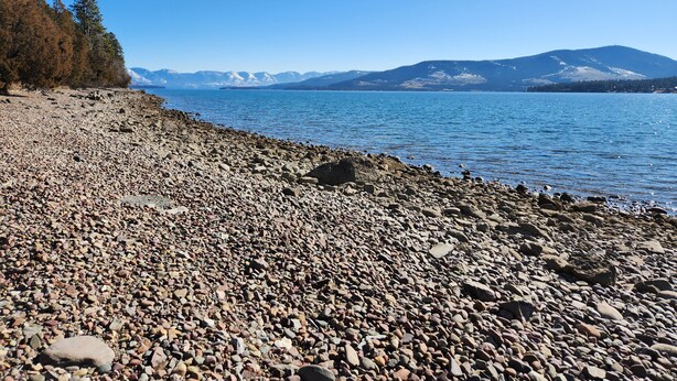A rocky shoreline with a clear view of mountains in the distance. - Shady Rest in Hot Springs MT. (Hot Springs)